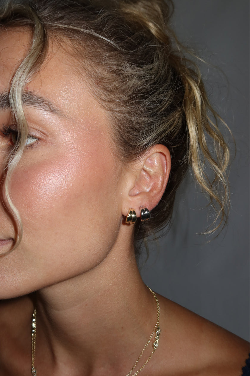 Close-up of a person with blonde hair and minimal makeup against a gray background